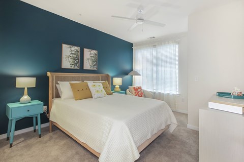 A bedroom with a bed, nightstand, and a ceiling fan.